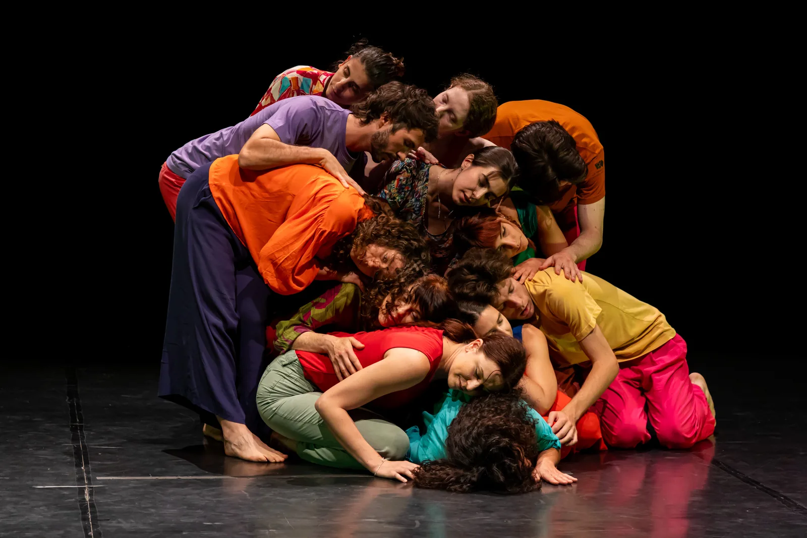 Danzatori in scena appoggiati gli uni sugli altri in un'unica forma di gruppo
